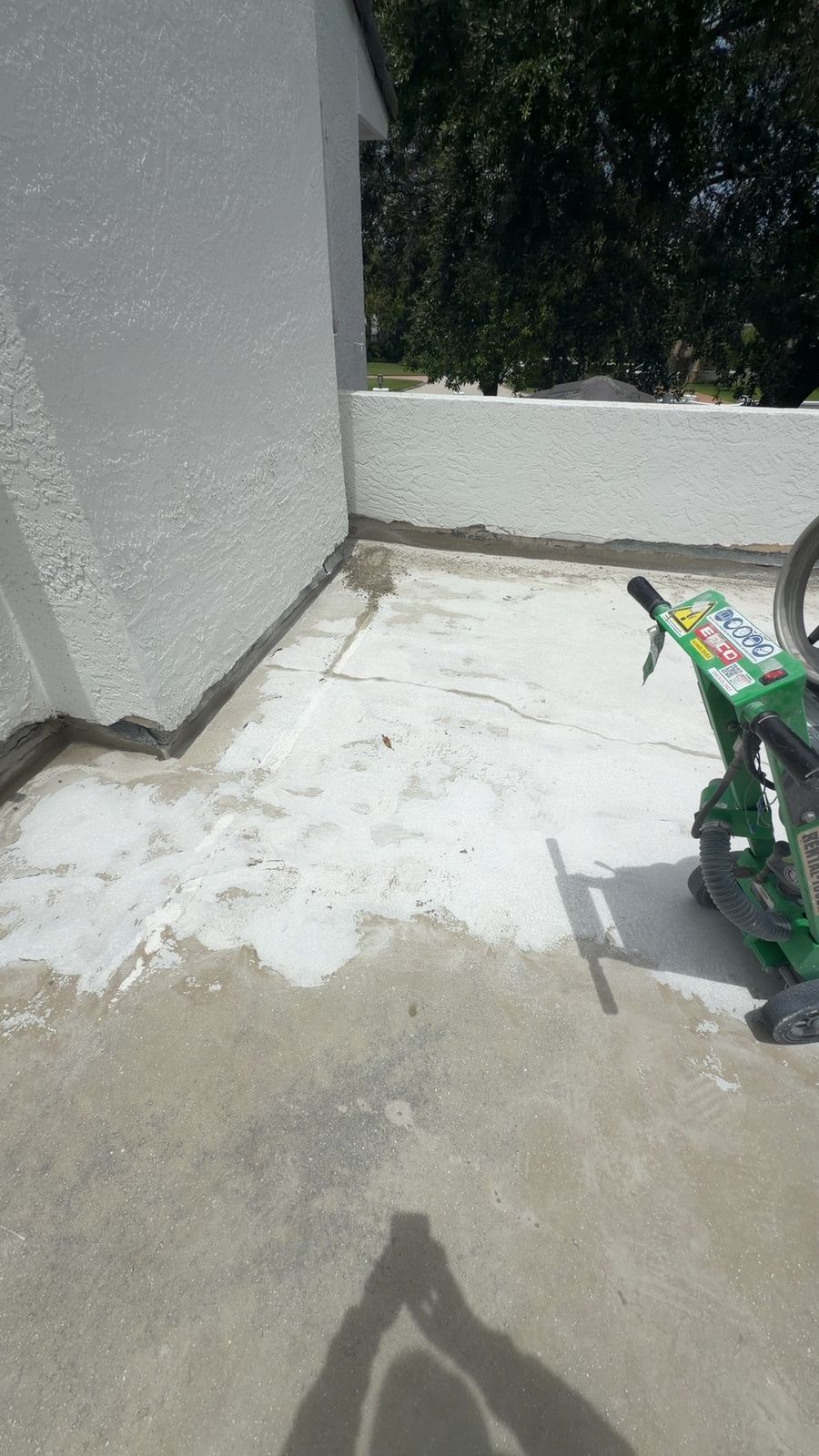 Ground concrete balcony corner prepped for waterproofing membrane, with the wall joint cleaned and sealed